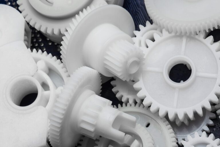 A close-up view of several white plastic gears of varying sizes, overlapping and arranged randomly.