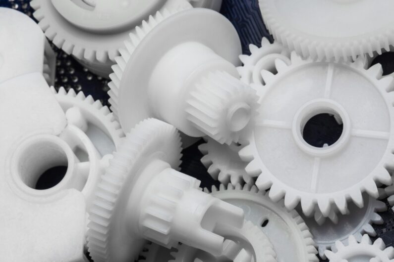 A close-up view of several white plastic gears of varying sizes, overlapping and arranged randomly.