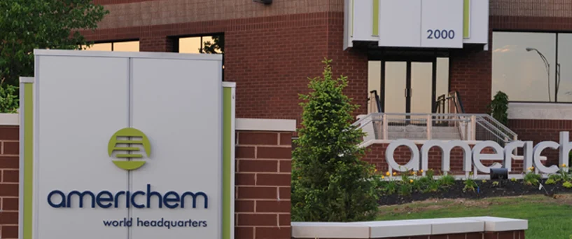 The entrance to Americhem World Headquarters with company signs, landscaping, and the building’s street number 2000 visible.