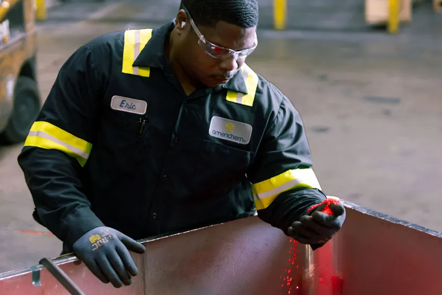 A worker wearing safety gear uses a handheld device to inspect or scan an item inside an industrial facility.