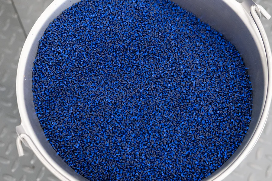A metal bucket filled with small blue plastic pellets, shown from above.