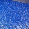 Close-up of numerous small blue plastic pellets scattered across a metal surface.