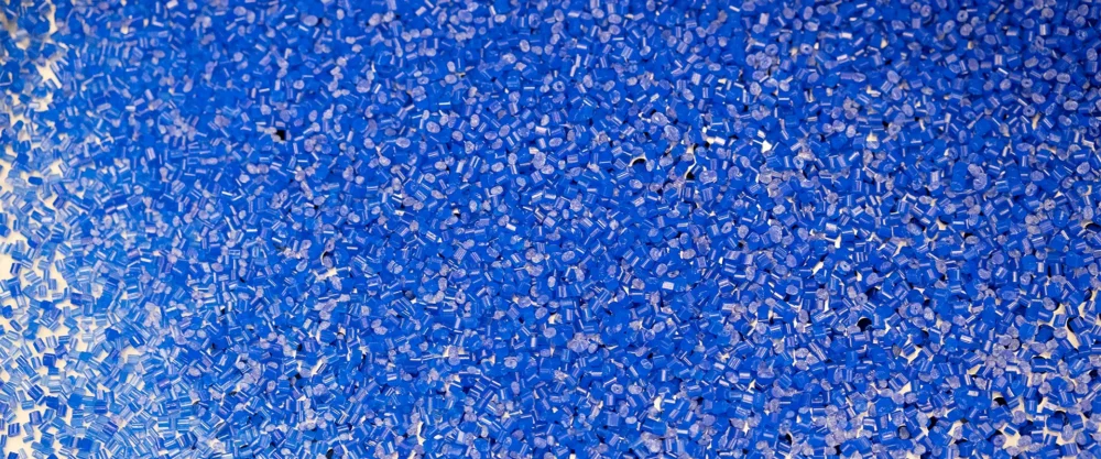 A close-up view of many small blue plastic pellets scattered across a surface.