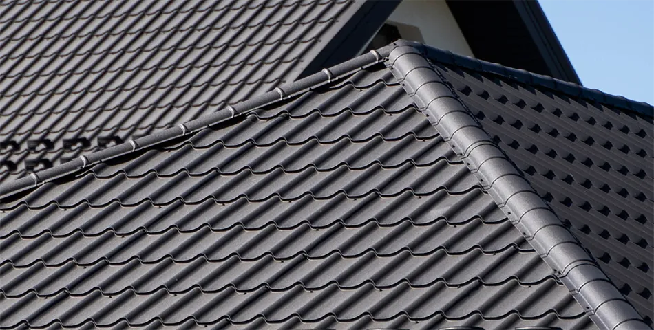 Close-up view of a house roof with overlapping gray ceramic or concrete roof tiles arranged in a neat pattern.