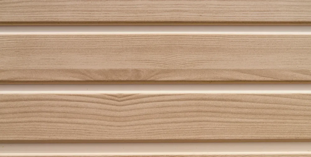 Close-up of beige wood-textured vinyl siding panels arranged horizontally with visible grain patterns and slight shadows between the panels.