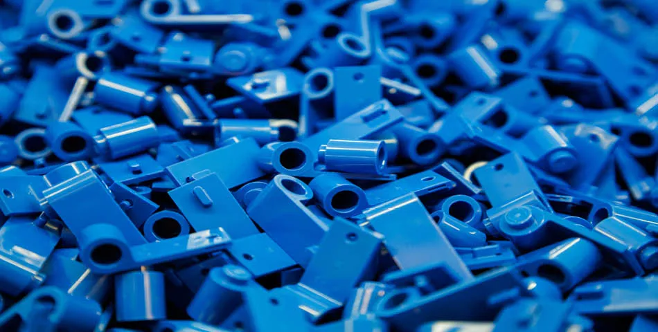 A pile of small blue plastic components with various shapes and holes, likely parts for assembly or construction.