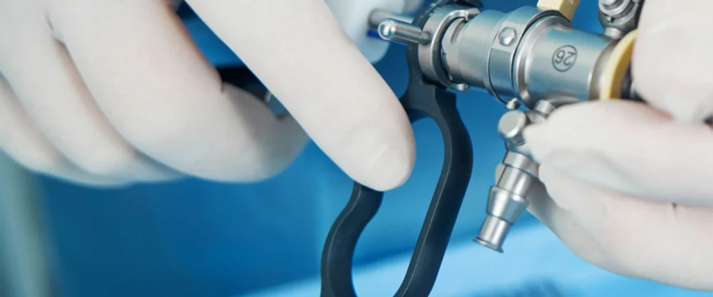 Gloved hands hold and adjust a surgical endoscope instrument during a medical procedure.