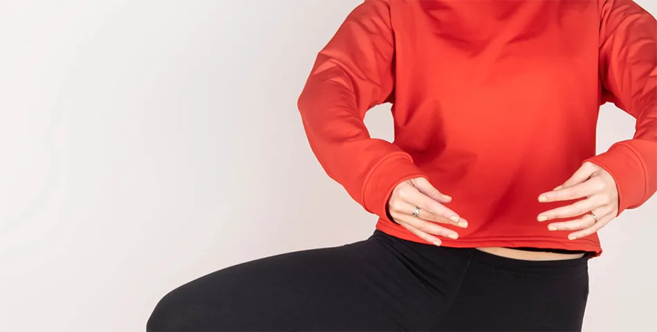 A person in a red long-sleeve shirt and black pants is posing with their arms bent and one leg raised. Their face is not visible.