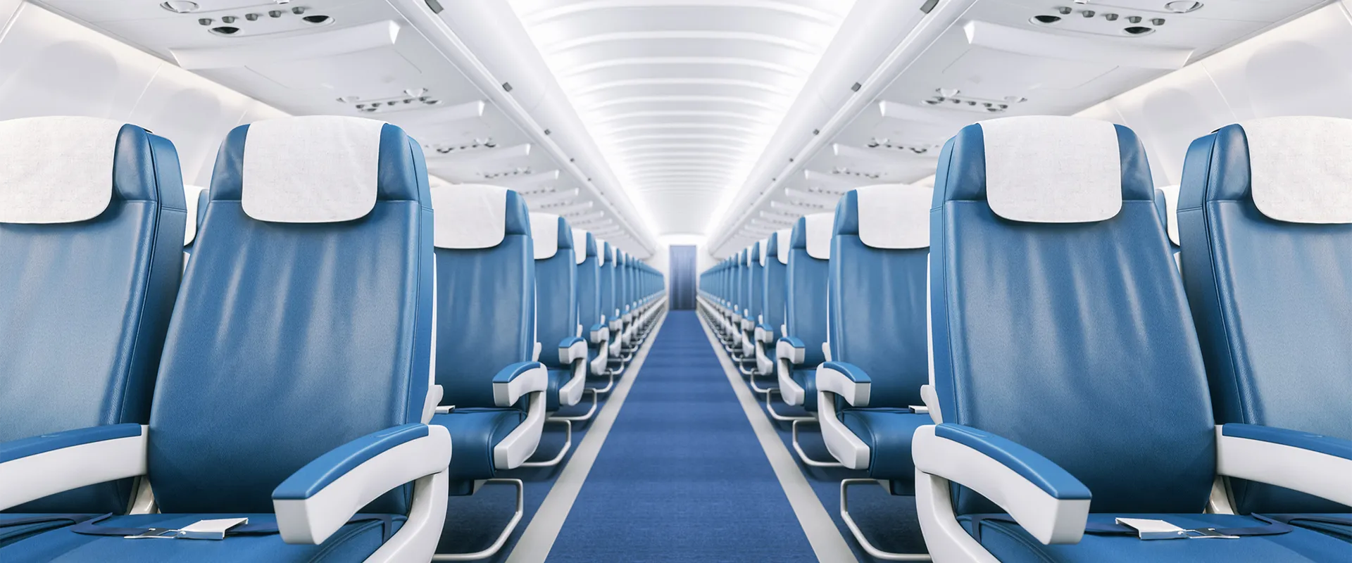 Interior view of an empty airplane cabin with rows of blue seats and white headrest covers, arranged on both sides of a central aisle.