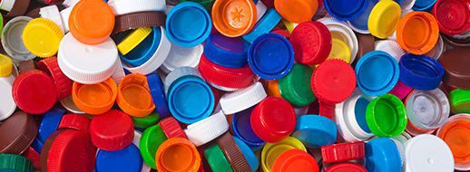 A large pile of assorted plastic bottle caps in various colors, shapes, and sizes.