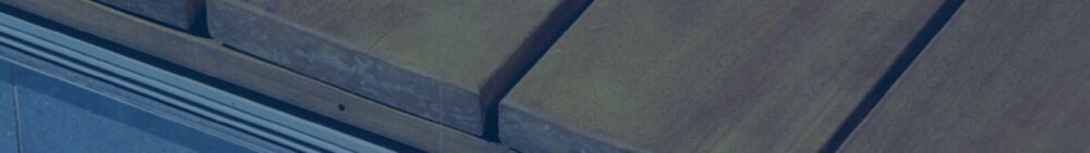 Close-up view of several parallel wooden planks with visible grain, separated by narrow gaps, likely forming part of a deck or boardwalk.