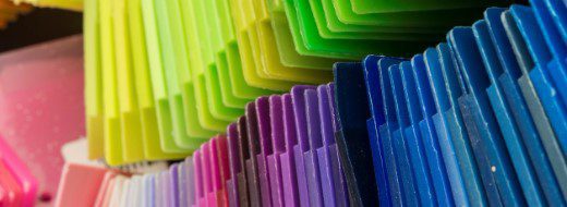 Close-up view of rows of colorful plastic sheets or tiles arranged in gradient order from yellow and green to blue and purple.
