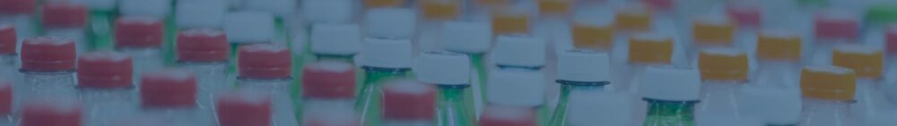 Rows of plastic bottles with white and orange caps are closely arranged, some filled with green or clear liquid.