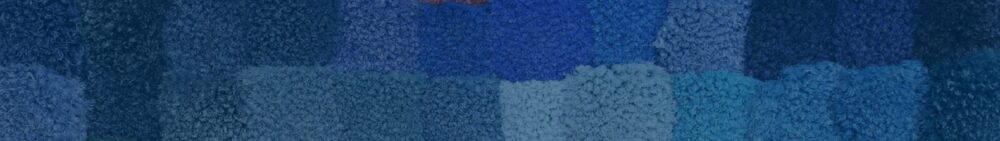 Close-up of a textured surface with rectangular patches in various shades of blue and a small hint of red at the top.