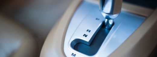 Close-up of a car’s automatic gear shift lever, showing the positions for Park (P), Reverse (R), Neutral (N), and Manual (M).