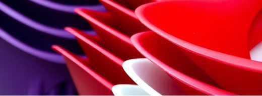 Close-up of overlapping, colorful plastic plates in red, white, and purple, creating an abstract, layered pattern.