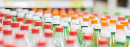 Rows of plastic bottles with red, white, and orange caps are arranged on a store shelf.