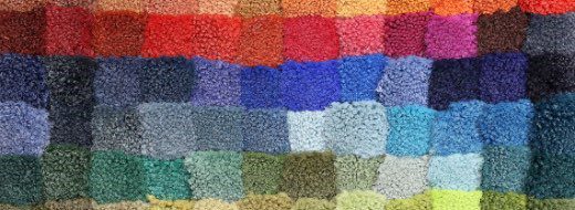 Rows of small, square carpet samples in a variety of colors displayed side by side in a grid pattern.