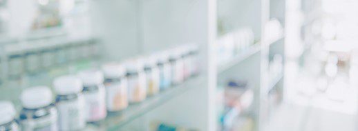 Blurred image of shelves with various bottles and containers, resembling a pharmacy or medical supply storage area.