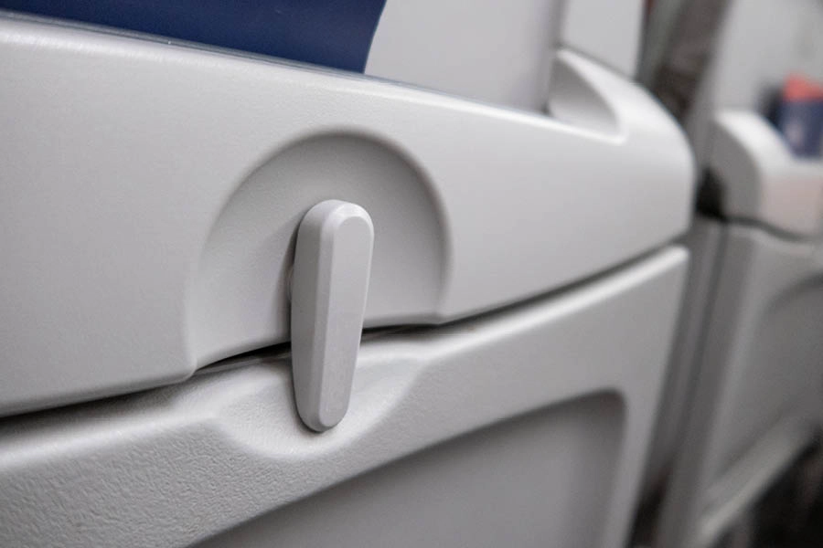 Close-up view of an airplane seatback tray table in its upright and locked position.