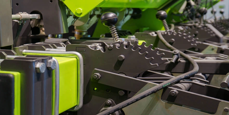 Close-up view of industrial machine components with green and black gears, levers, and cables.