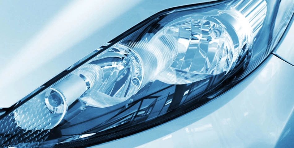 Close-up view of a modern car headlight with reflective surfaces and blue-tinted lighting.