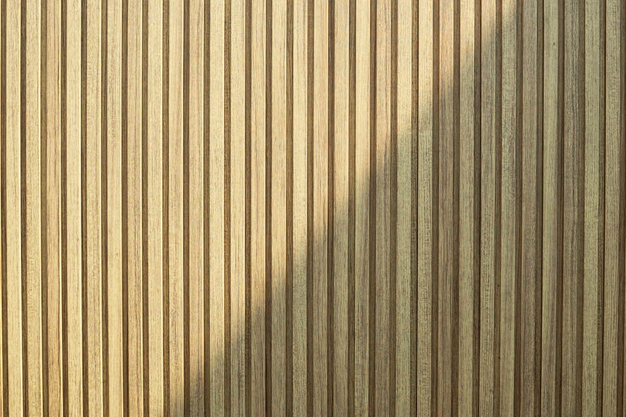 Vertical wooden slats with a diagonal shadow cast across the right side of the surface.