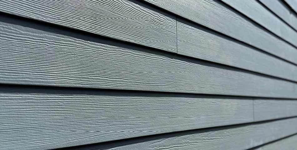 Close-up view of gray horizontal fiber cement siding panels with a woodgrain texture.