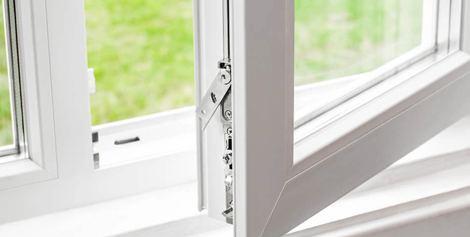 A close-up view of a white, open tilt-and-turn window with a grassy lawn visible outside.