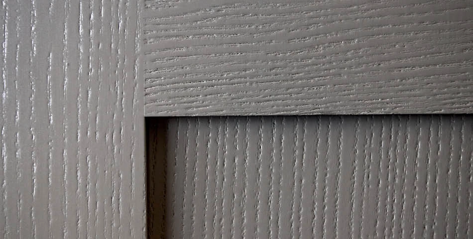 Close-up of gray wooden panels with a textured, grooved surface and overlapping sections.
