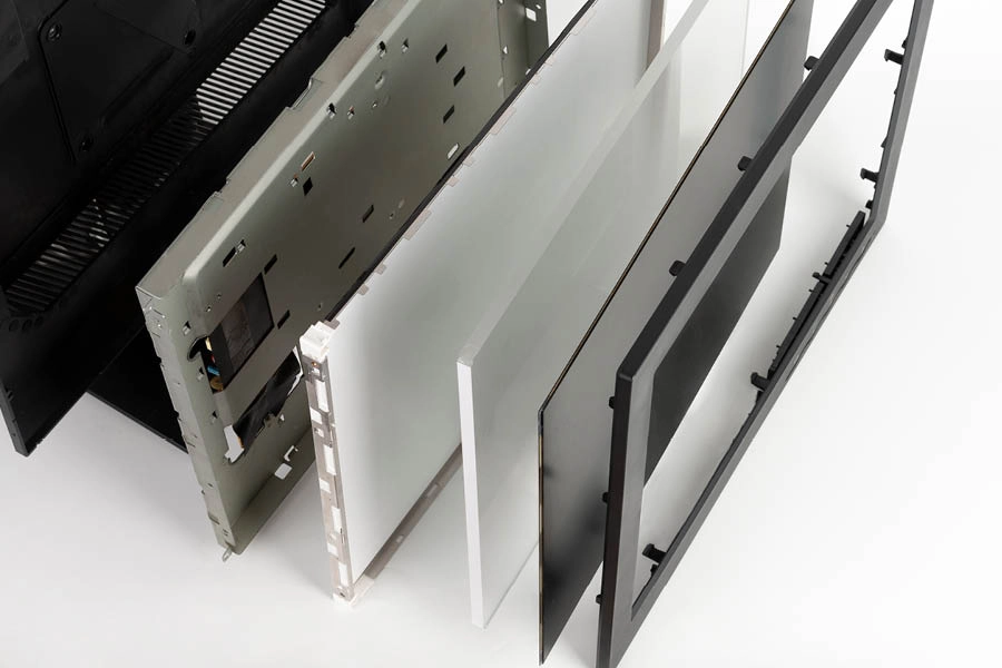 An exploded view of a flat-screen television showing separated front and back panels, internal layers, and electronic components on a white background.