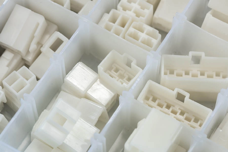 A close-up view of various white plastic electrical connectors organized in separate compartments of a storage tray.
