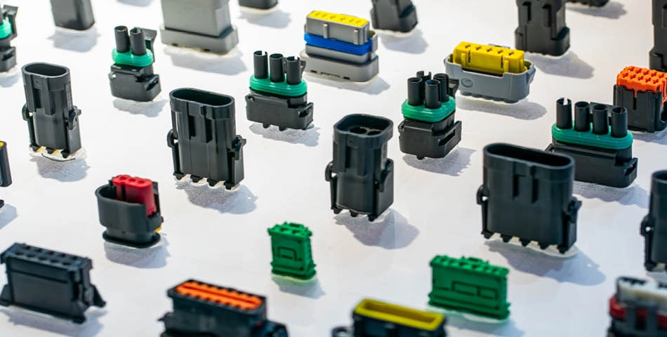 A variety of electrical connectors of different shapes, sizes, and colors are arranged on a white surface.