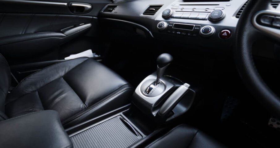 Interior of a car showing black leather seats, center console with automatic gear shift, and dashboard controls.