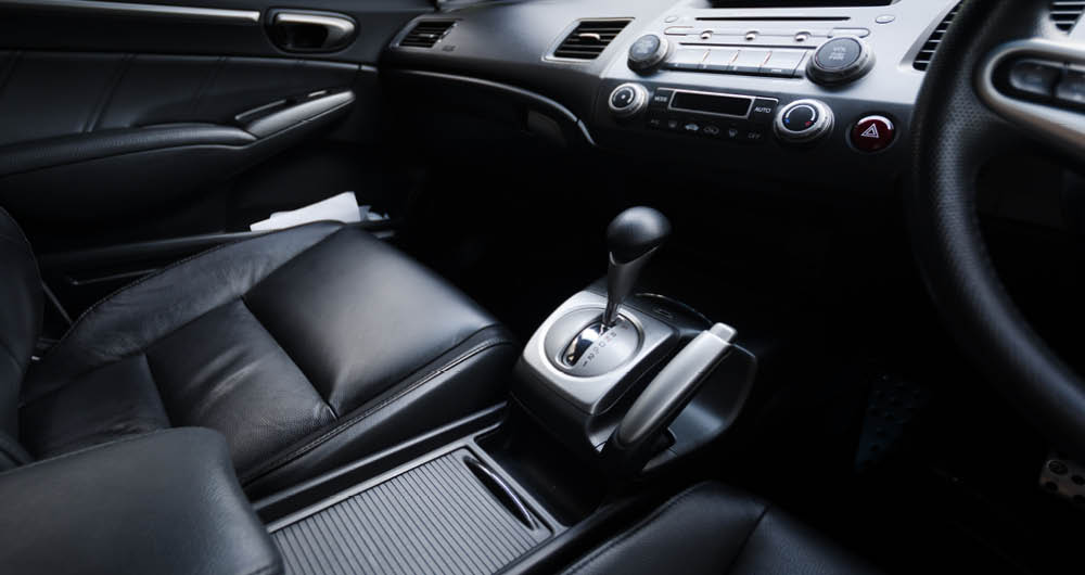 Interior of a car showing black leather seats, center console with automatic gear shift, and dashboard controls.