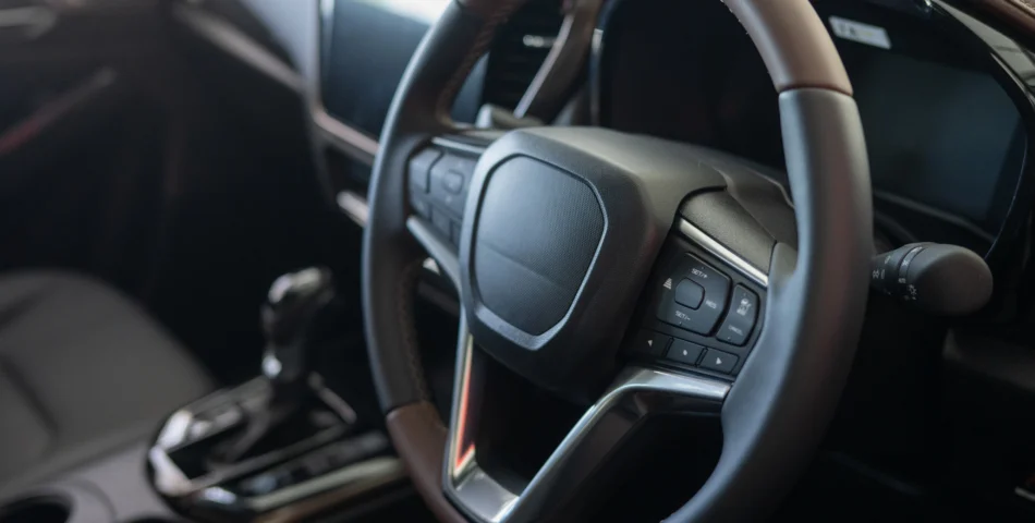 Close-up view of a modern car's steering wheel and dashboard interior, including control buttons and gear shift.