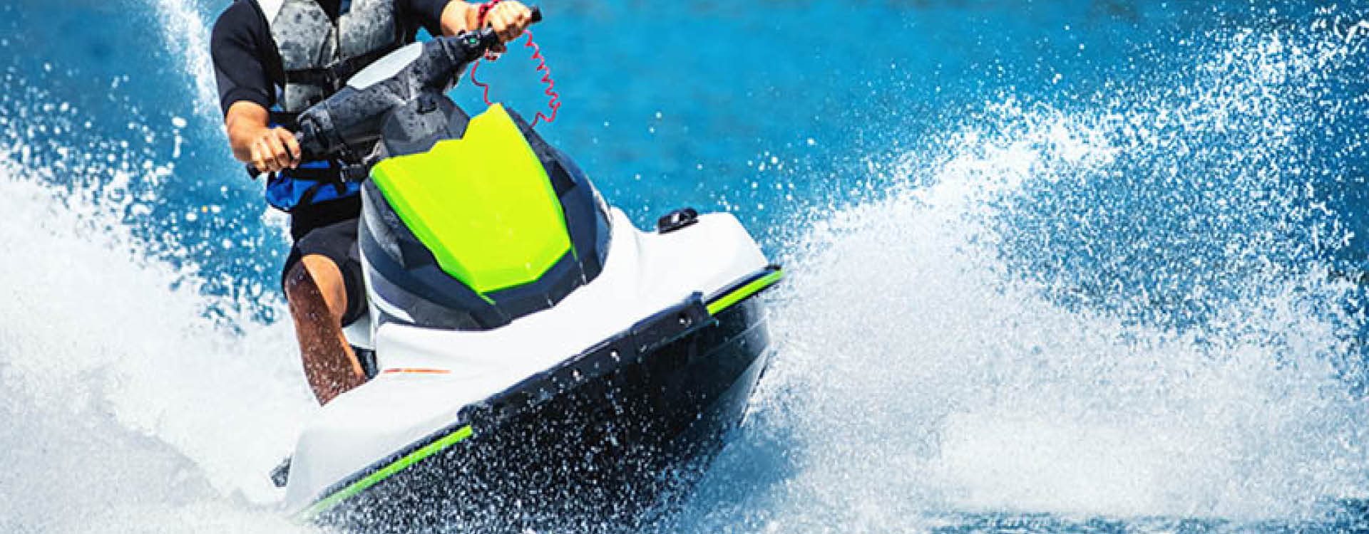 Person riding a white and green jet ski on blue water, creating splashes and waves.