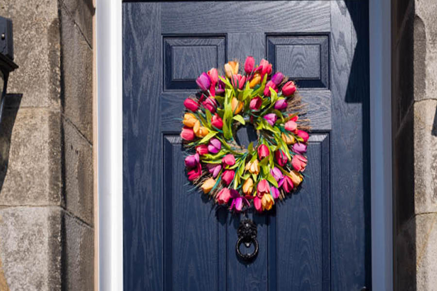 A dark blue door with a multicolored tulip wreath hanging in the center.