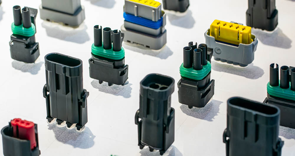 A variety of electrical connectors of different shapes, sizes, and colors are arranged on a white surface.