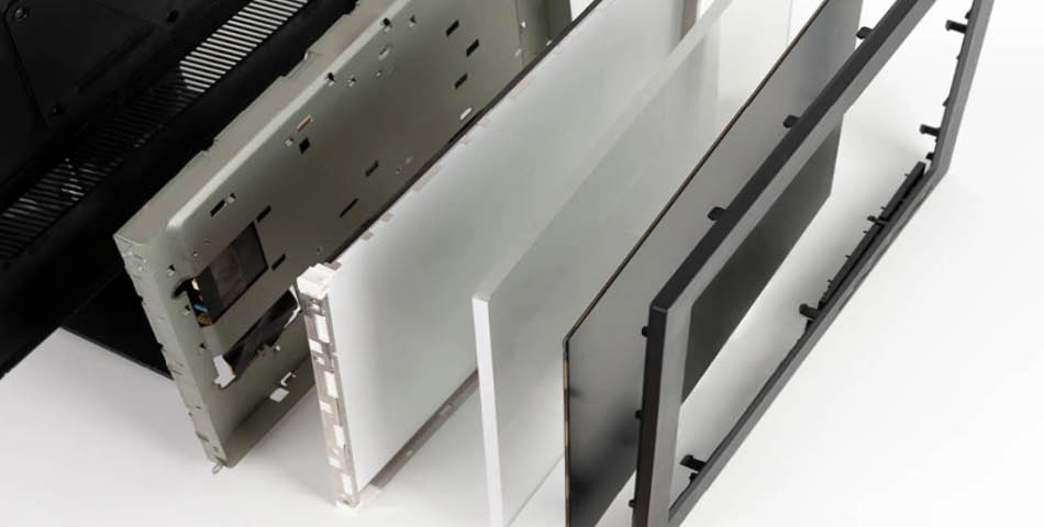 Several separated layers and components of a flat screen television are arranged in a row, showing the inner and outer parts.