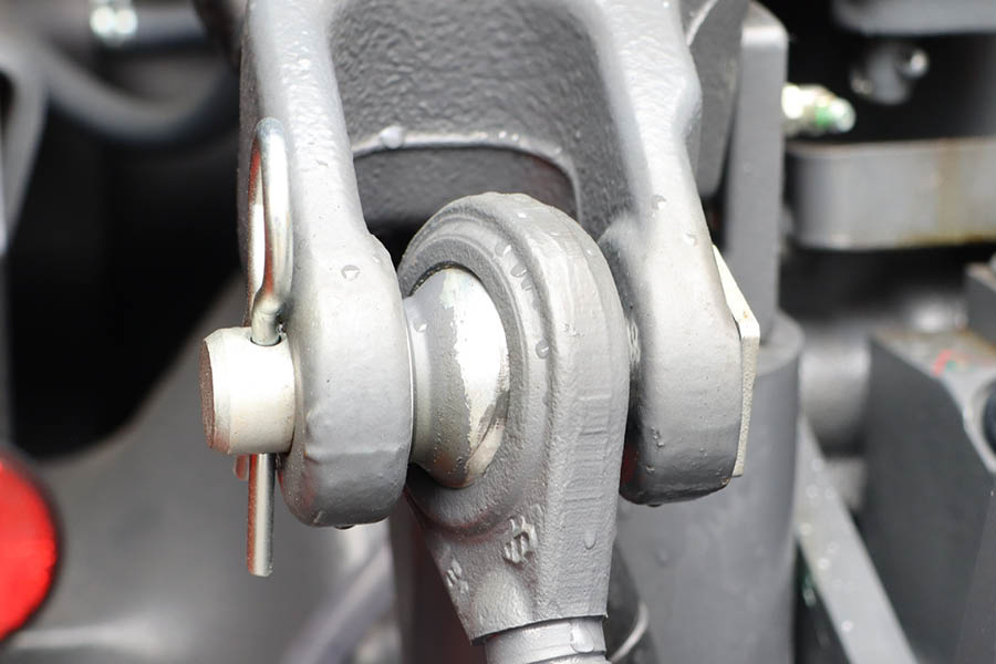Close-up view of a metal mechanical linkage joint with a secured pin, showing surface texture and slight wear.