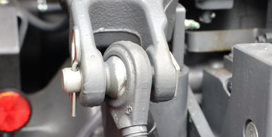 Close-up of a gray metal mechanical joint with a pin and circular bearing, possibly part of industrial machinery or heavy equipment.