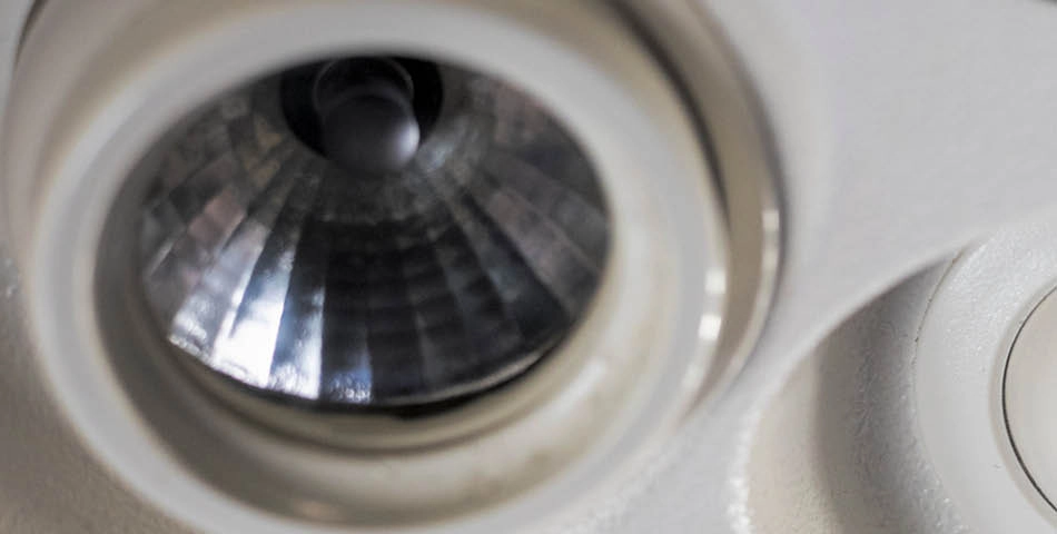 Close-up view of a recessed light fixture with a reflective interior and a circular outer edge, installed in a white ceiling.
