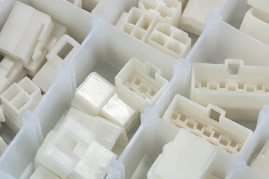 Assorted white plastic electrical connectors organized in compartments of a storage box.
