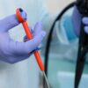 A person wearing medical gloves holds and operates an endoscope, a flexible medical instrument used for internal examinations.