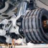 Close-up view of an aircraft landing gear showing multiple large rubber tires, metallic parts, and hydraulic components.