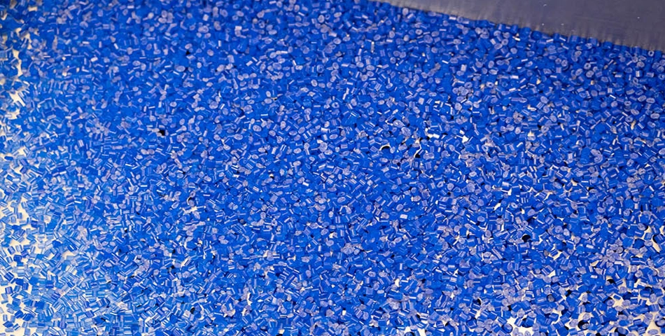 A large quantity of small, blue plastic pellets spread out on a flat surface.