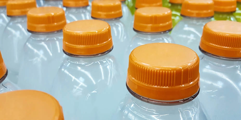 Close-up of several plastic bottles with orange caps arranged in rows.