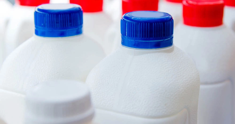 Close-up of several plastic milk jugs with blue and red caps.