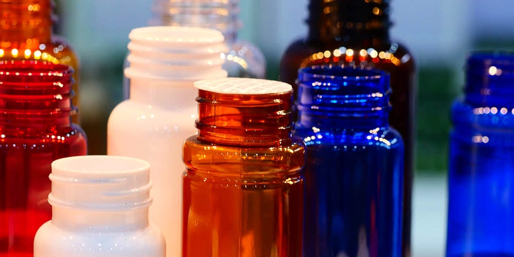 Assorted empty plastic bottles in white, amber, and blue colors are displayed upright, with some open and some closed.